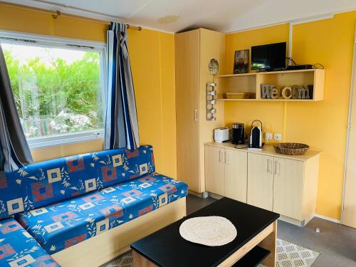 un salon avec un canapé bleu et une fenêtre dans l'établissement Mobilhome Harmonie, à Biscarrosse