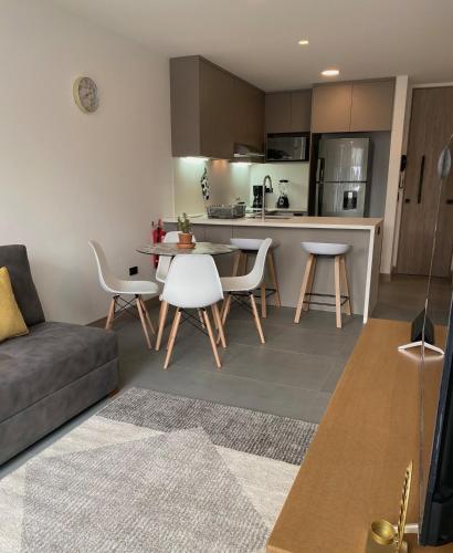 a living room with a couch and a table and chairs at Suite de lujo con balcón en Edificio NEO in Quito