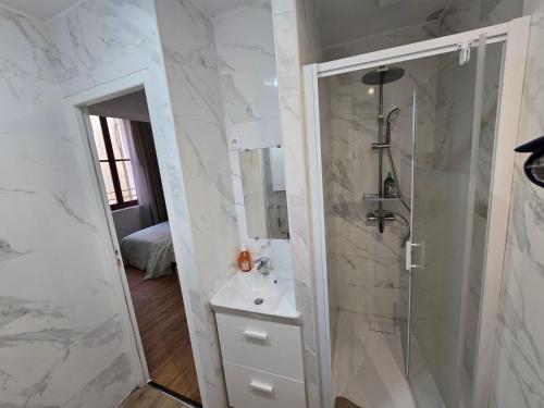 une salle de bain blanche avec une douche et un lavabo dans l'établissement E1 - Charmant studio en intramuros, rénové climatisé, à Avignon