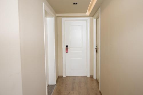 an empty hallway with a white door and wooden floors at 4R Colombo Hotel in Tirana