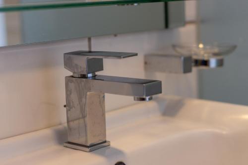 a bathroom sink with a chrome faucet and a mirror at Karen Plains Hotel Nairobi in Nairobi