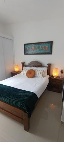 a bed in a room with two lamps on the side at atardeceres in Armenia