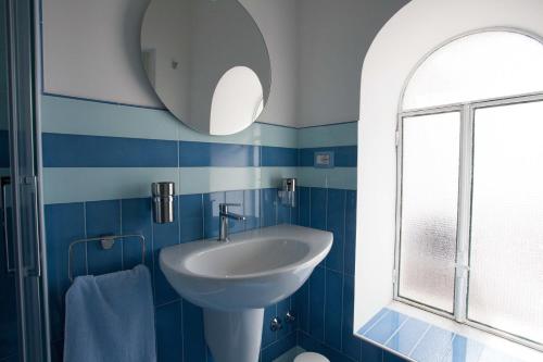 een blauwe en witte badkamer met een wastafel en een spiegel bij A casa di Laura in Amalfi