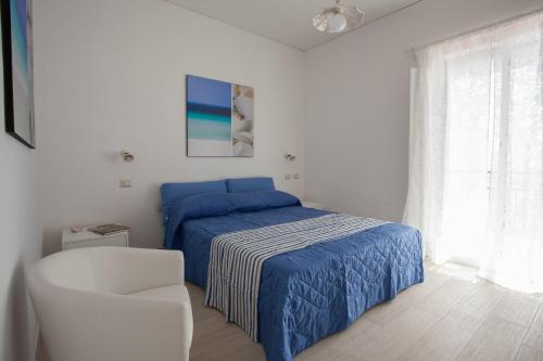 een slaapkamer met een blauw bed en een witte stoel bij A casa di Laura in Amalfi