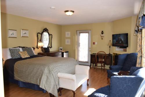 a bedroom with a bed and chairs and a television at Auberge Wild Rose Inn in Moncton