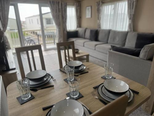a dining room table with plates and glasses on it at Golden Palm Resort - The Haywood - Coastal Caravan Breaks in Chapel Saint Leonards