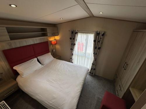 a bedroom with a large bed and a window at Golden Palm Resort - The Haywood - Coastal Caravan Breaks in Chapel Saint Leonards