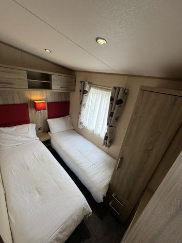 a bedroom with two beds in a trailer at Golden Palm Resort - The Haywood - Coastal Caravan Breaks in Chapel Saint Leonards