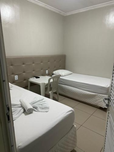 a room with two beds and a table and a chair at PRINCESA HOTEL Russas in Russas