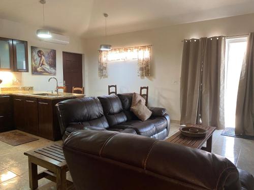 a living room with a leather couch and a kitchen at Luxurious One Bedroom Poolside Punta Chame Resort in Pajonal