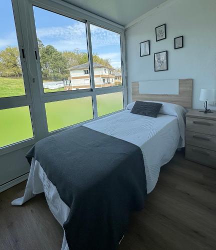 a bedroom with a bed and a large window at PortoHome Ático in Portomarin