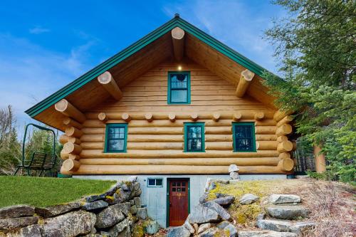 a log cabin with blue windows and a red door at Eaglet Log Home in Franconia
