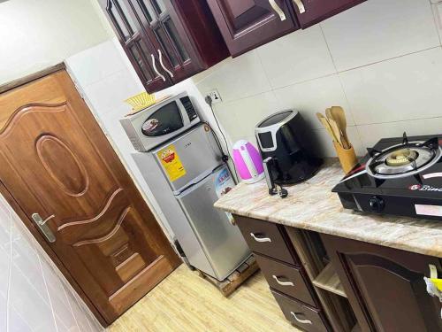 a small kitchen with a stove and a refrigerator at Cozy 2 bedroom apartment in Accra