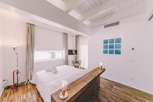 una camera bianca con un letto e una grande finestra di Suite 10 Home Design & Spa a Polignano a Mare