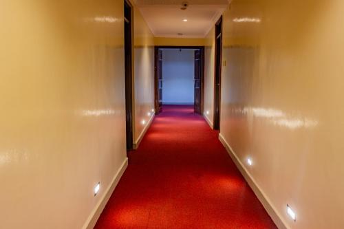 a long corridor with a red carpet and a door at Karen Plains Hotel Nairobi in Nairobi