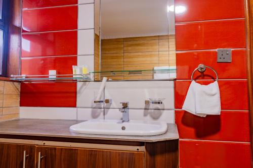a bathroom with a sink and a red wall at Karen Plains Hotel Nairobi in Nairobi