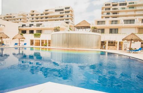 a large swimming pool in front of a building at Ocean view condo with balcony hotel zone Cancun in Cancún