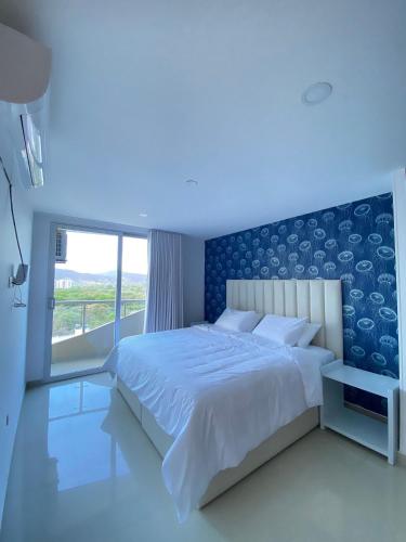 Playa Bello HorizonteU-GO Oasis: Encanto y Confort Frente al Mar en Santa Marta的卧室里有一张白色的大床，墙壁是蓝色的