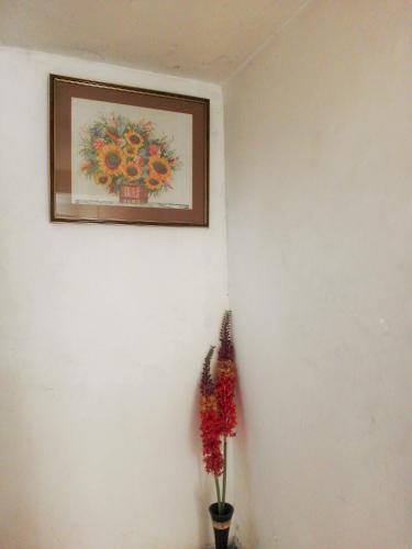 a picture hanging on a white wall with flowers at Villa Two Residence in Mount Lavinia
