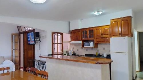 Una cocina con gabinetes de madera y un refrigerador blanco. en Esencia de Montaña, en El Challao