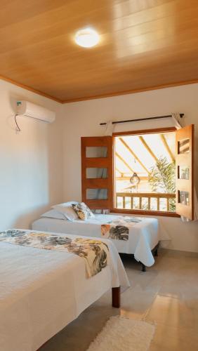 a bedroom with two beds and a window at Encanto do Mar Pousada, Nova Caraiva -BA in Caraíva