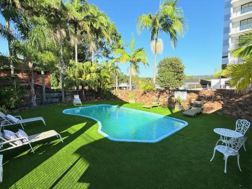 a swimming pool in a yard with palm trees at Gosford Palms Motor Inn in Gosford