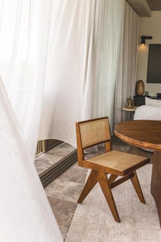 a rattan chair and a table in a bedroom at NACRE curated luxury - steps to the beach - heated pool in Marcoola