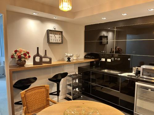 a kitchen with black cabinets and a table at Center Suiço Flats in Campos do Jordão
