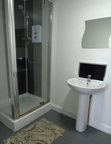 a bathroom with a shower and a white sink at OYO Victoria Apartments in Middlesbrough
