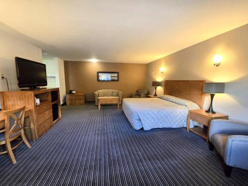 a hotel room with a bed and a flat screen tv at Breeze Inn Hotel in Seward
