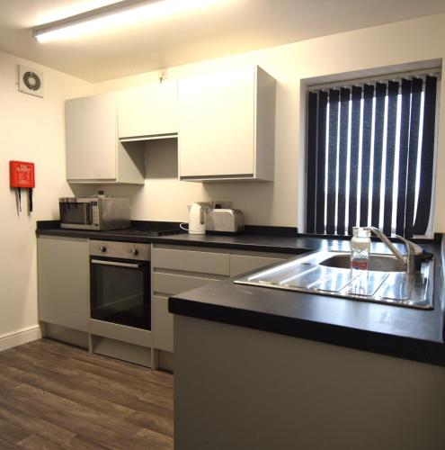 a kitchen with white cabinets and a sink at OYO Victoria Apartments in Middlesbrough