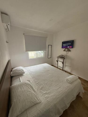 een slaapkamer met een groot wit bed met een raam bij Casa Naay in Cancun
