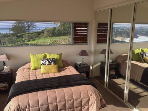 Waiheke IslandにあるView43 Beach Houseの大きなベッドと大きな窓のある寝室