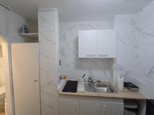 Il comprend une cuisine avec un évier et des murs en marbre blanc. dans l'établissement E0 - Beau studio en intramuros, rénové climatisé, à Avignon