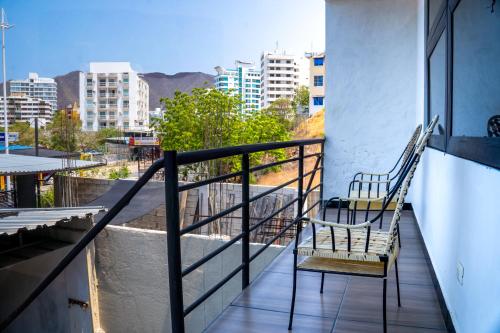 two chairs on a balcony with a view of a city at Hotel Family House Rodadero in Santa Marta