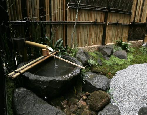 a pond in a garden with rocks and a fence at Bliss INN Kuromon ブリスイン黒門 in Osaka