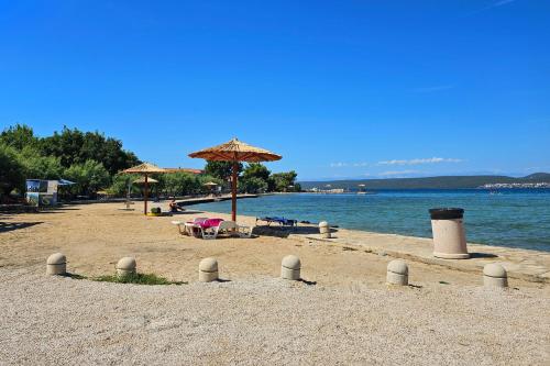 a beach with umbrellas and chairs and the water at Apartments by the sea Nevidjane, Pasman - 18427 in Neviđane