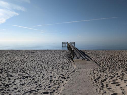 a sandy beach with a pier and the ocean at Cozy, designed, Beach House apartment in Beddinge Strand