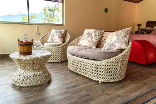 a living room with three wicker chairs and a table at Finca alto Bonito Jacuzzi Piscina y WiFi in Tenza