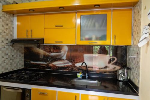 a kitchen with yellow cabinets and a sink at Finca alto Bonito Jacuzzi Piscina y WiFi in Tenza