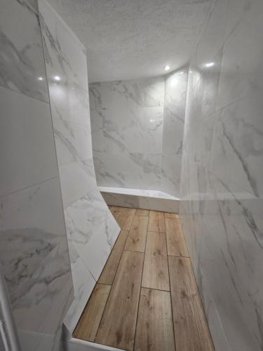 La salle de bains est pourvue de murs en marbre blanc et de parquet. dans l'établissement E2 - Elégant appartement neuf intramuros climatisé, à Avignon