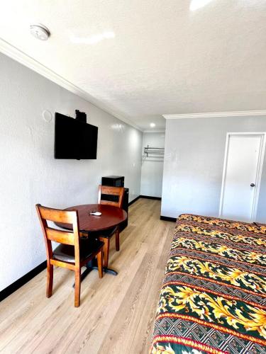 a hotel room with a table and a bed and a desk at Aqua Inn Motel in El Monte
