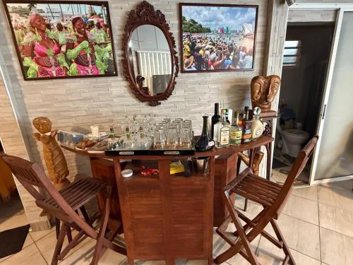 a bar with two chairs and a table with bottles at residence caramboles in Fort-de-France