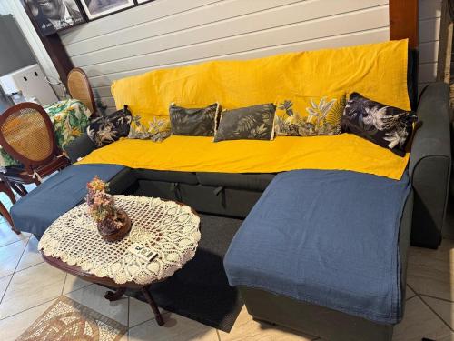 a bed with a yellow blanket and a table at residence caramboles in Fort-de-France