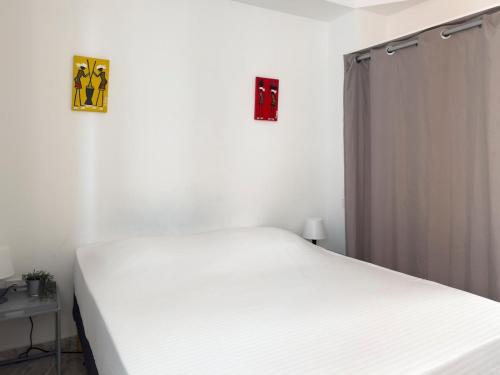 a white bed in a bedroom with two pictures on the wall at Spacious 3-bdr apartment - Palmarejo Grande - LCGR in Praia