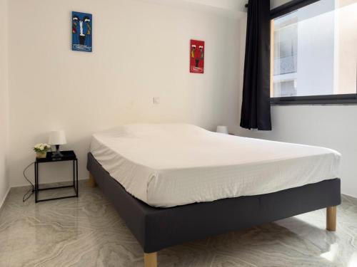 a bedroom with a bed with white sheets and a window at Spacious 3-bdr apartment - Palmarejo Grande - LCGR in Praia