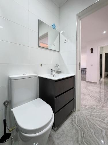 a white bathroom with a toilet and a sink at Spacious 3-bdr apartment - Palmarejo Grande - LCGR in Praia