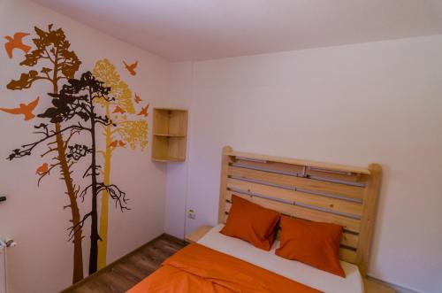 ein Schlafzimmer mit einem Bett mit orangefarbenen Laken und einem Baum-Wandbild in der Unterkunft Activ Parc in Negreşti