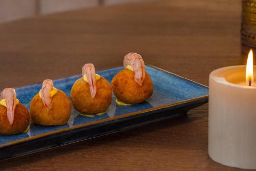 a blue plate with five food items on a table with a candle at Kimpton Los Monteros Marbella by IHG in Marbella