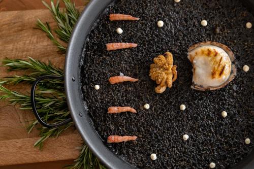 a pan full of food with carrots and garlic at Kimpton Los Monteros Marbella by IHG in Marbella